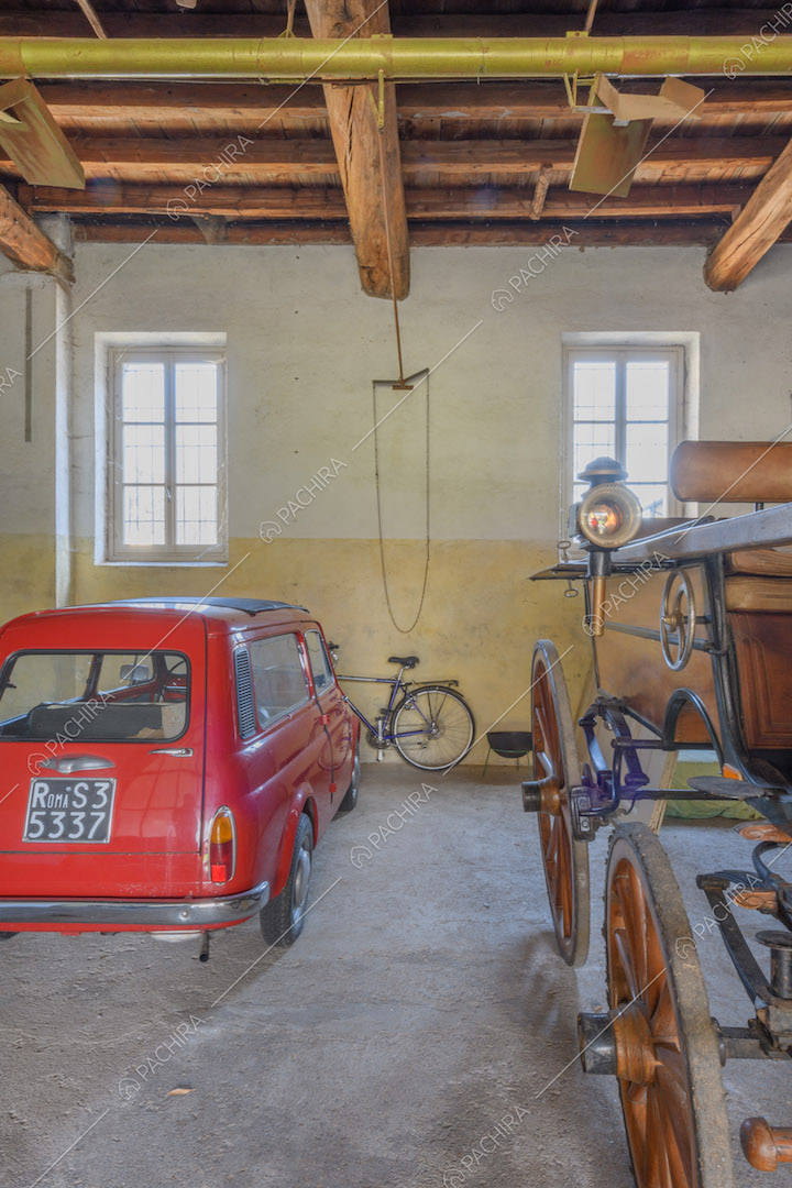 Garage con soffitto in travi in legno a vista e pareti gialle e bianche