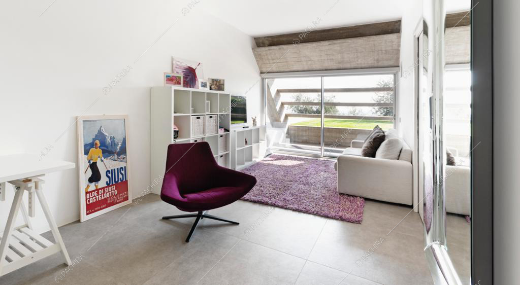 Divano bianco sopra al tappeto viola e poltroncina di design