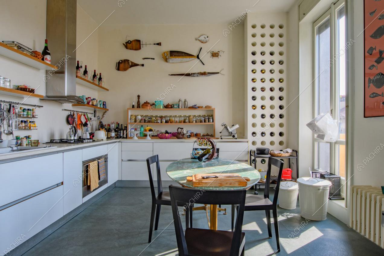 Tavolo da pranzo con piano in marmo verde nella cucina a parete con fornelli a gas
