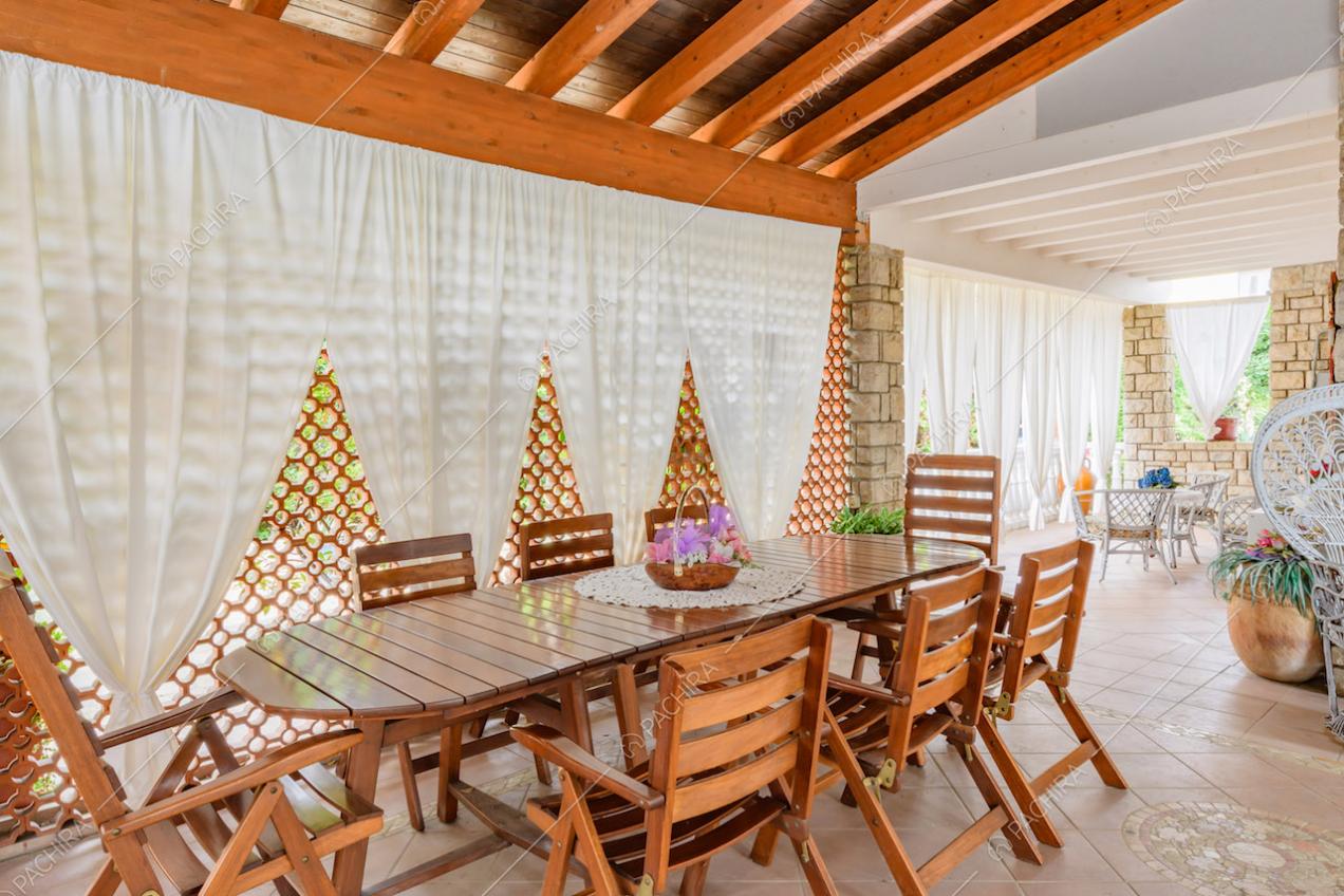 Tavolo da pranzo e sedie in legno nella veranda con travi a vista