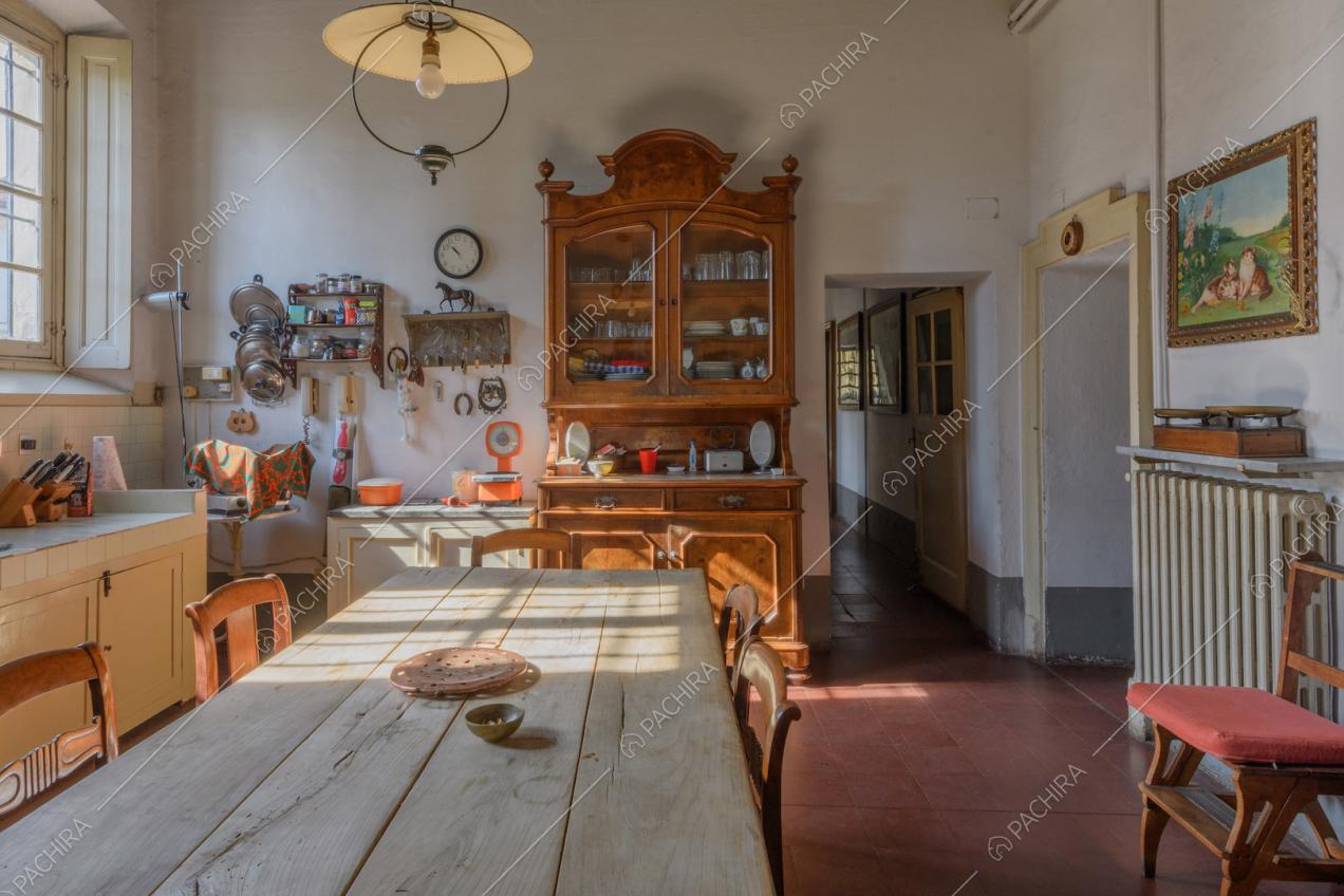 Grande cucina bianca a parete con tavolo da pranzo in legno e pavimento in cotto