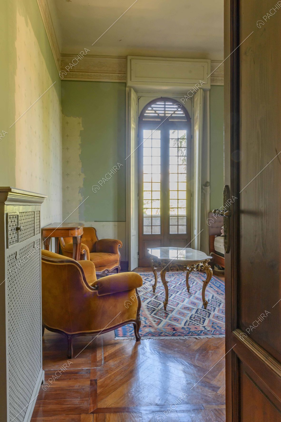 Vista sul salotto dalle pareti verdi e dal pavimento in parquet