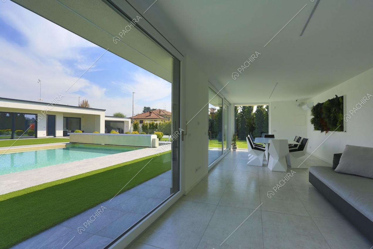 Sala da pranzo dalle ampie vetrate e scorcio sulla piscina tramite le ampie vetrate