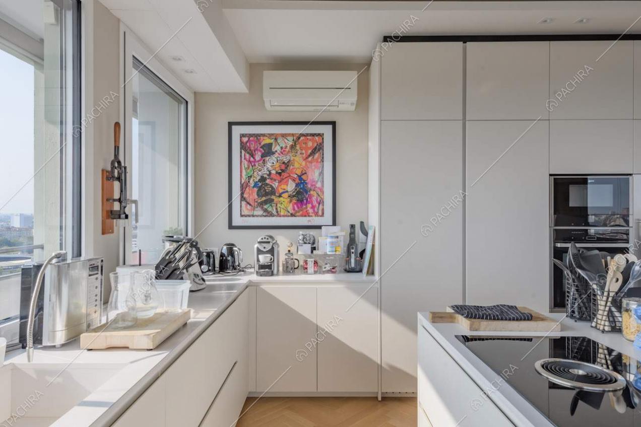 Pavimento in parquet nella cucina bianca a isola con fornelli a induzione