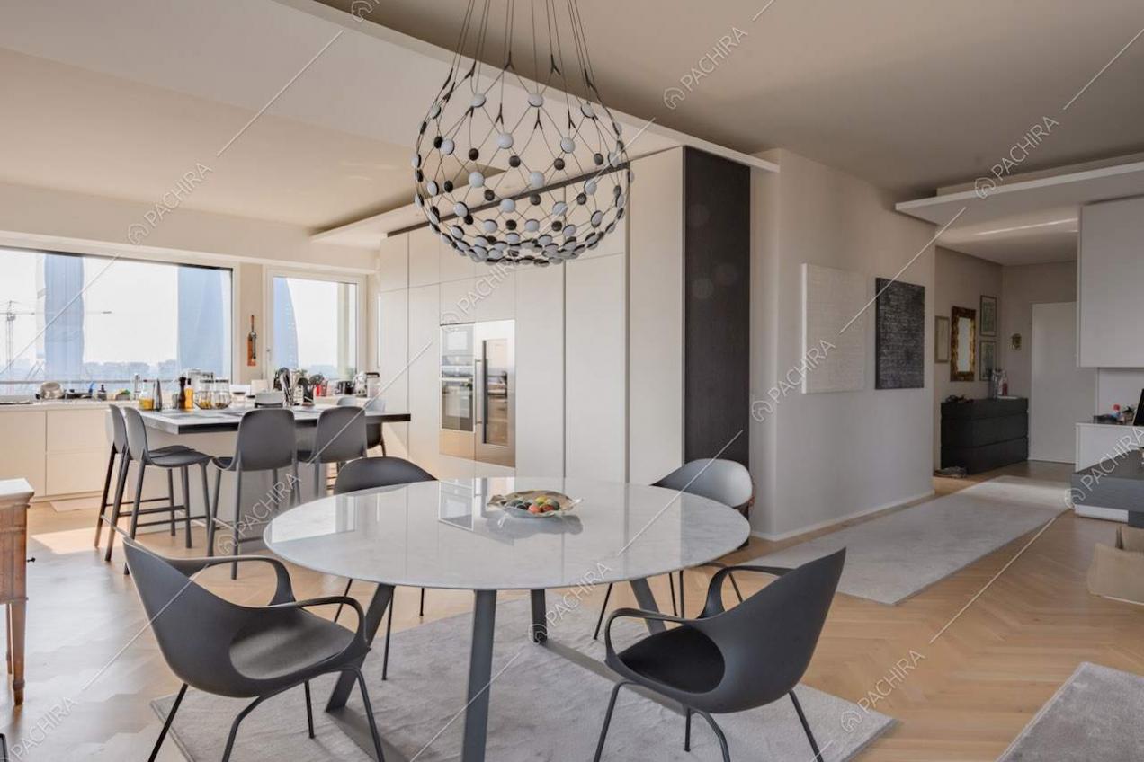 Luminosa zona living con pavimento in parquet a spina di pesce e tavolo da pranzo rotondo
