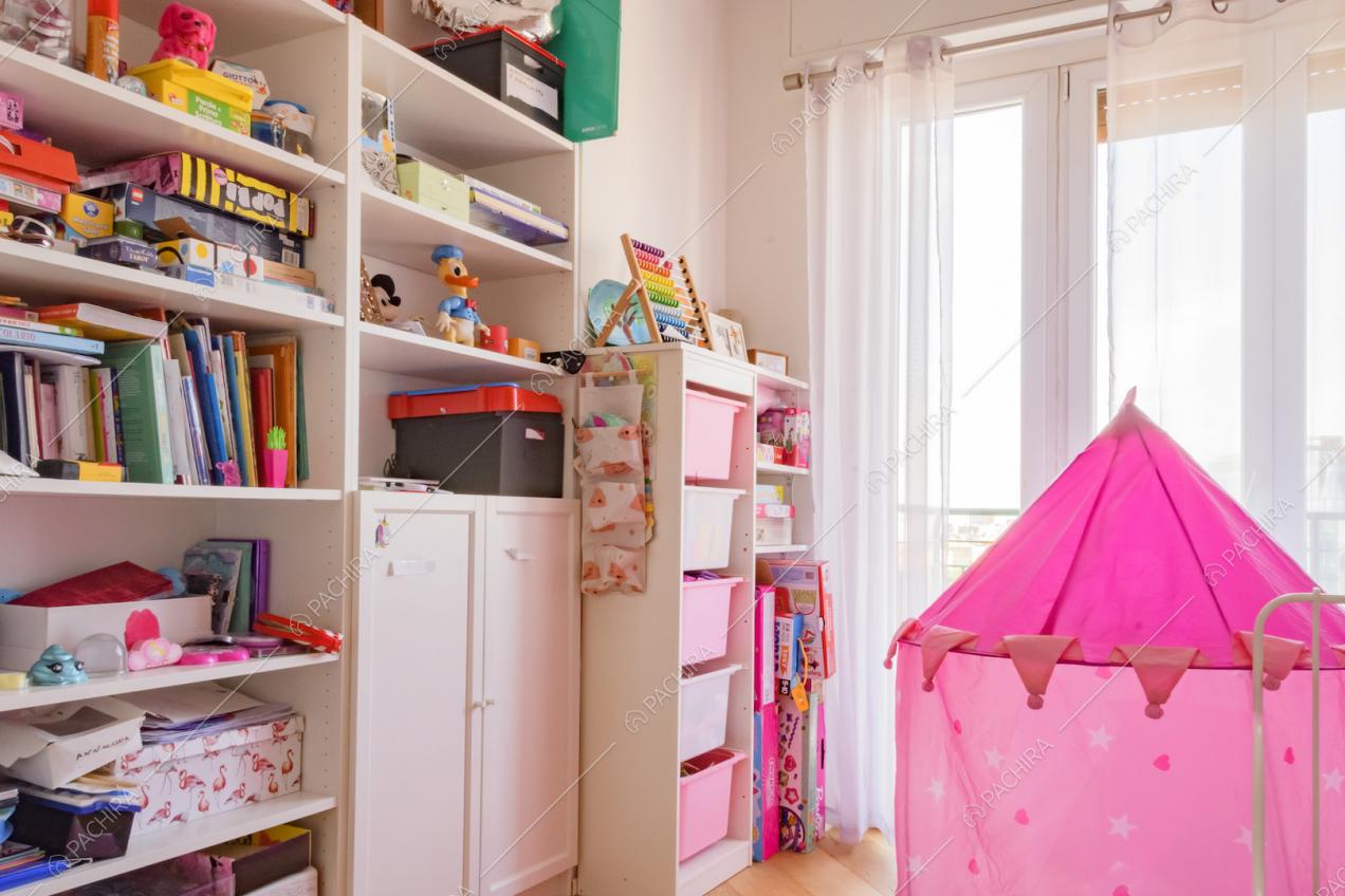 Scaffale bianco con libri e giochi nella cameretta