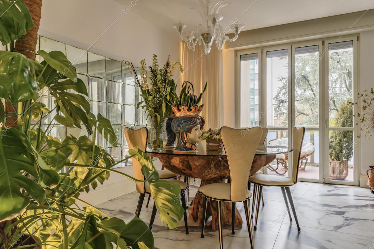 Tavolo da pranzo in legno, sedie bianche di design e specchiera délabré nella sala dal pavimento in marmo
