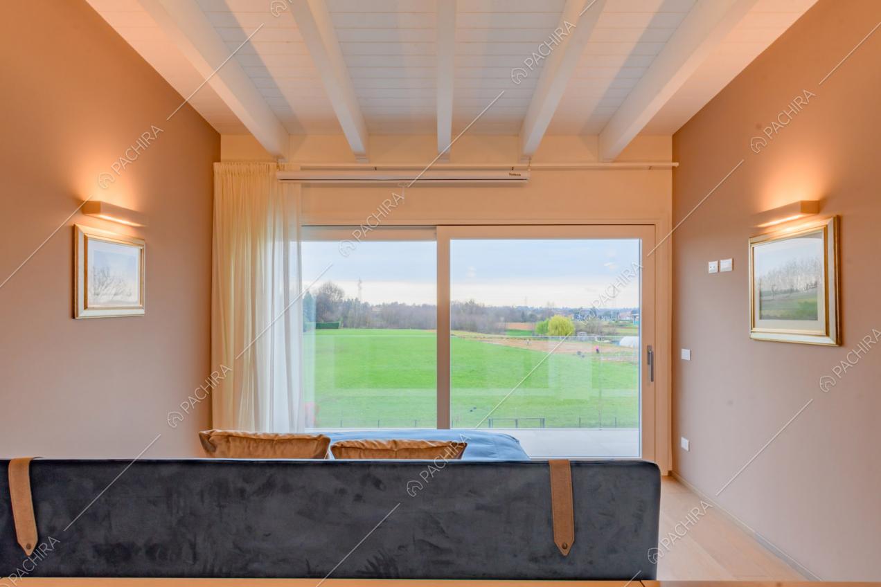 Camera da letto matrimoniale con porta-finestra scorrevole e travi a vista sul soffitto