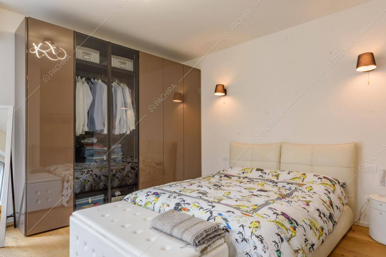 Luminosa camera da letto matrimoniale con pareti bianche e pavimento in parquet
