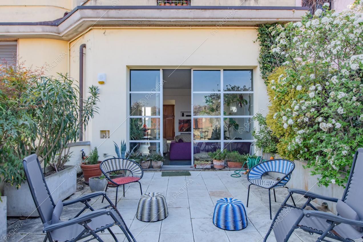 Terrazza con fioriere, sdraio e porta-finestra in stile industriale