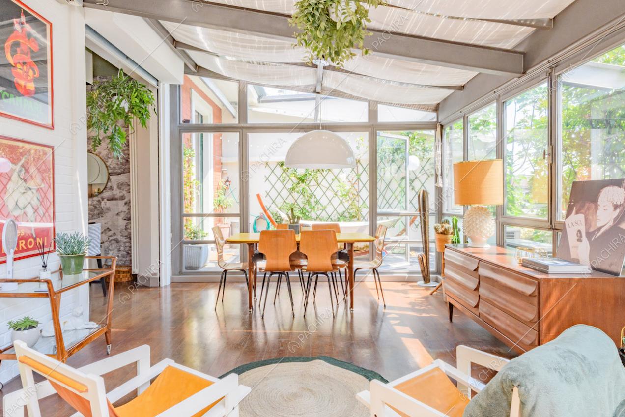 Luminosa veranda con tavolo da pranzo giallo, lampadario e pavimento in parquet