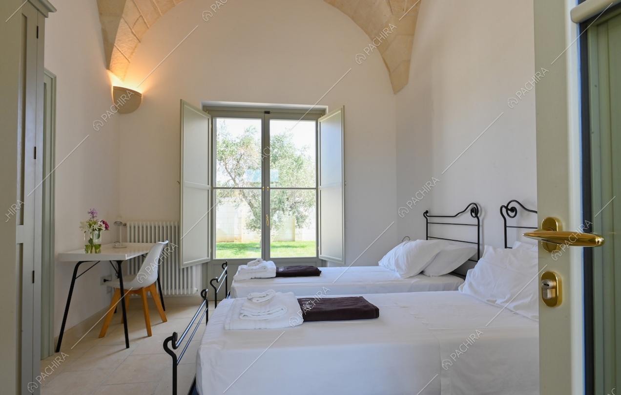 Camera da letto doppia con scrivania, pareti bianche e soffitto ad arco