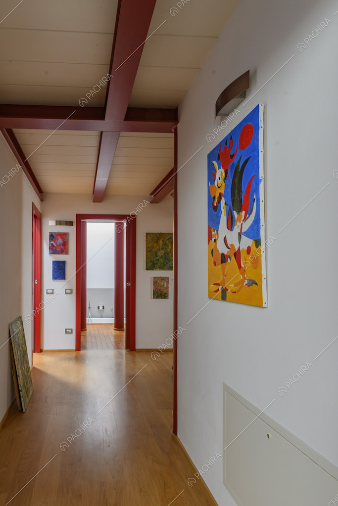 Corridoio con pavimento in parquet, pareti bianche e infissi rossi