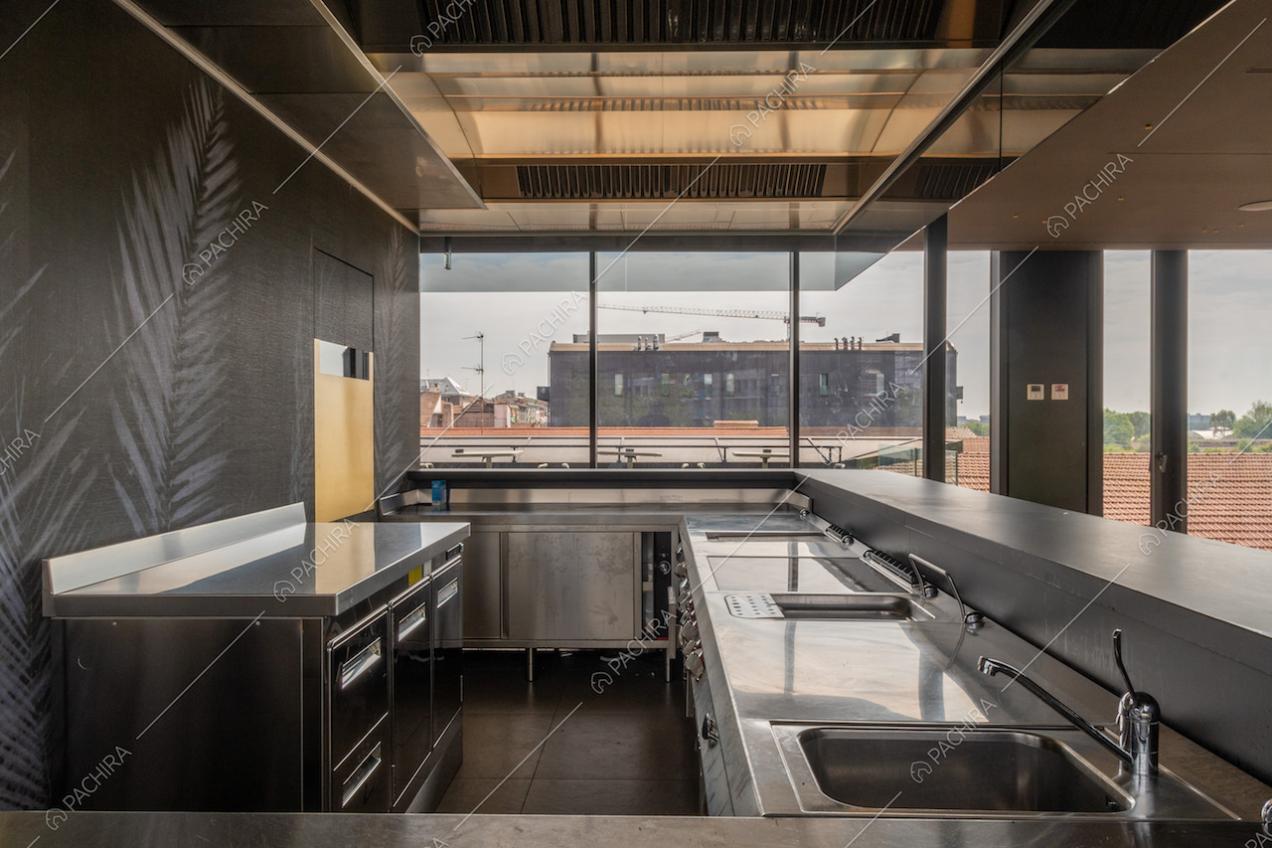 Cucina industriale della location con fornelli a induzione, carta da parati e vetrate