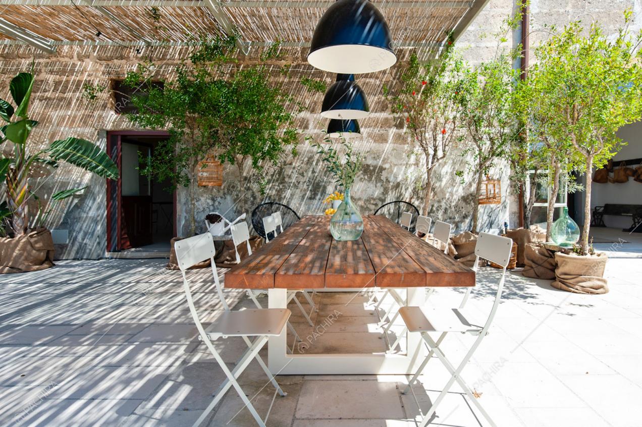 Zona pranzo esterna con tettoia in bambù, lampade e piante in vaso