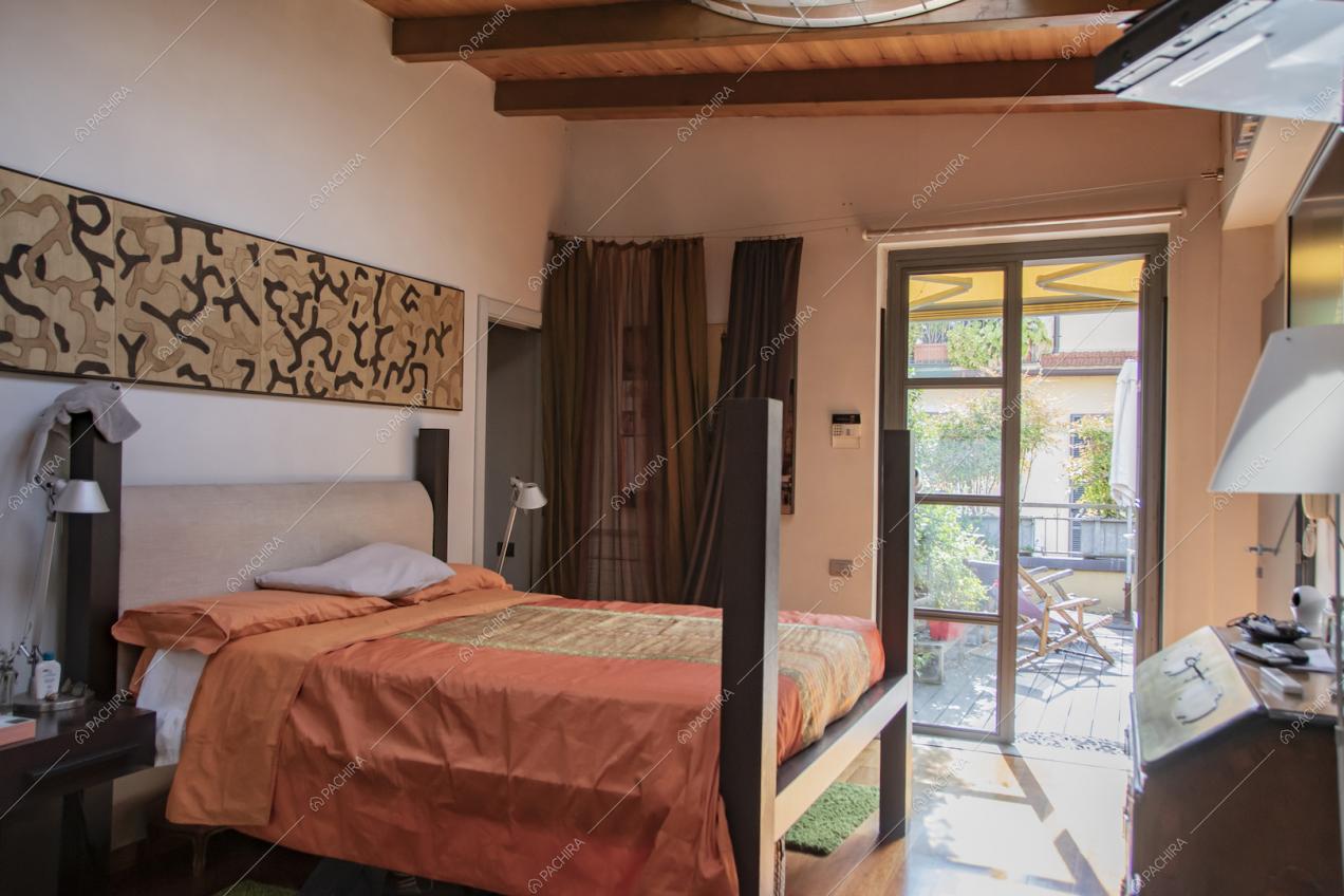 Luminosa camera da letto matrimoniale con porte-finestre per accedere alla terrazza e pareti bianche