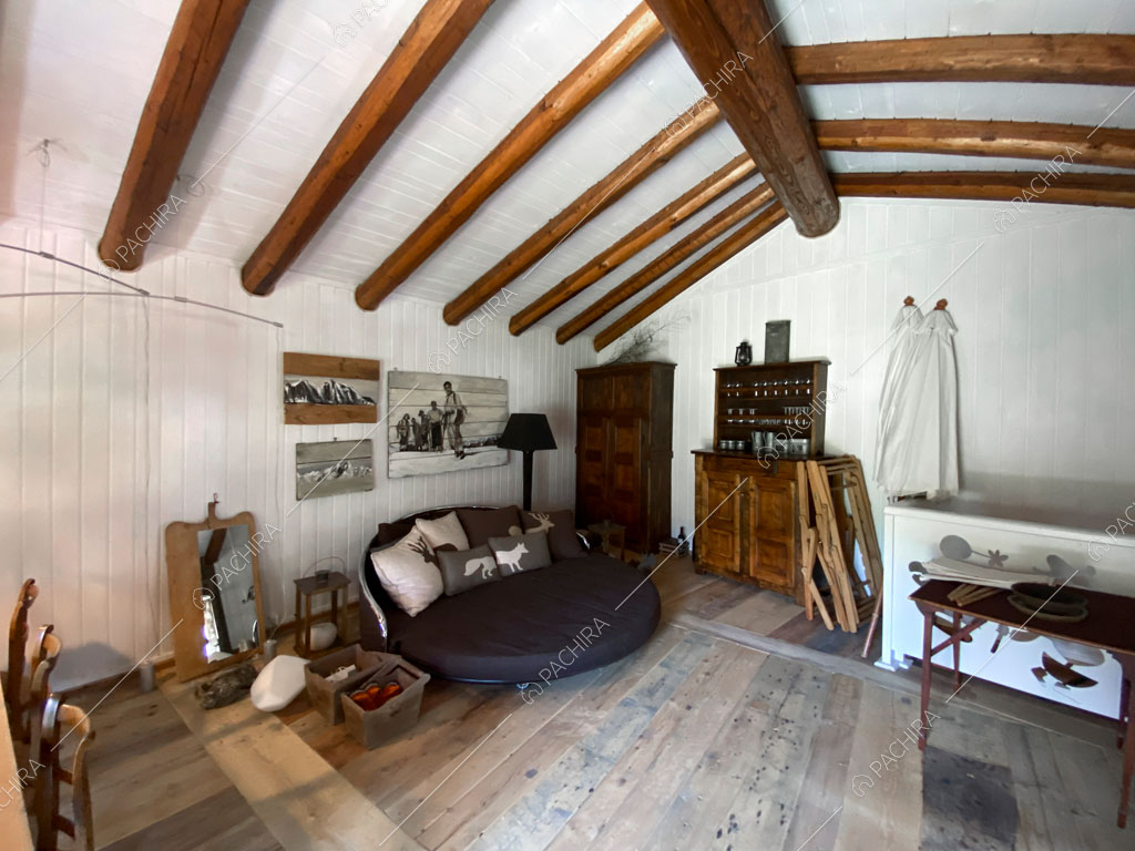 Sala con travi a vista sul soffitto dello chalet Thar, location in stile rustico ad Aosta
