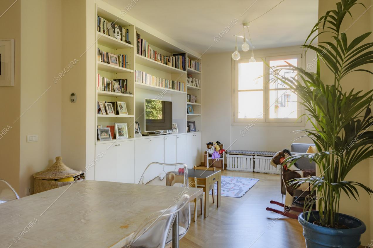 Libreria contenente libri e portafoto di fianco alla finestra quadrata