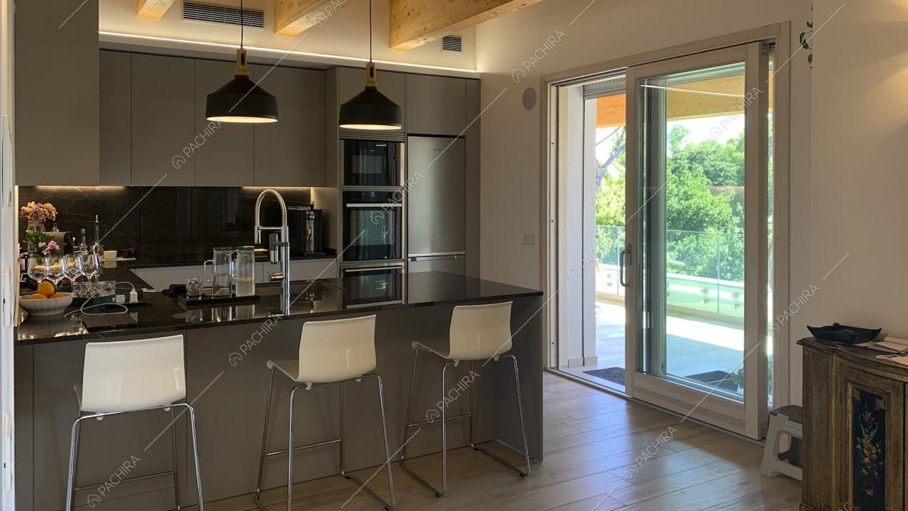 Cucina con penisola nei toni del grigio con sgabelli alti bianchi e lampade a sospensione