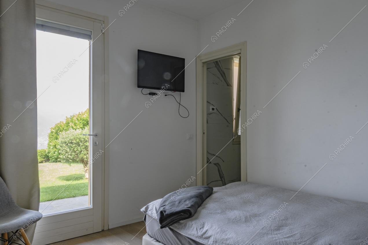 Letto singolo e piccolo televisore appeso alla parete