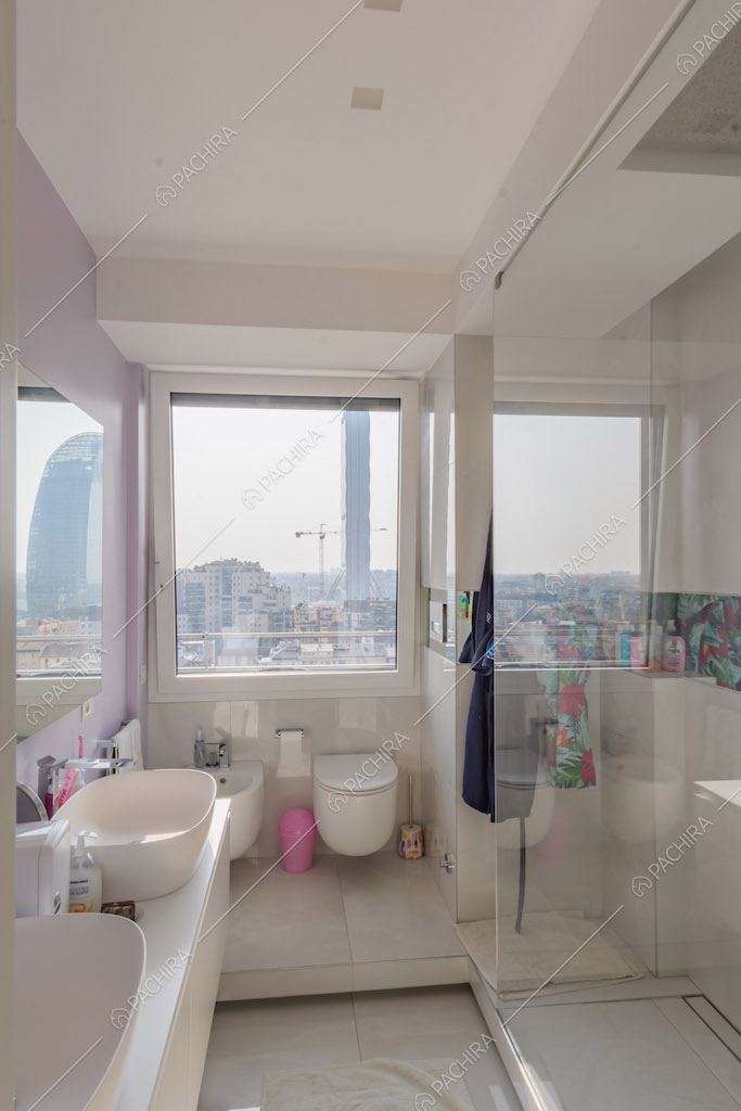 Luminoso bagno con doppio lavandino, box doccia e vetrata con vista sullo skyline 