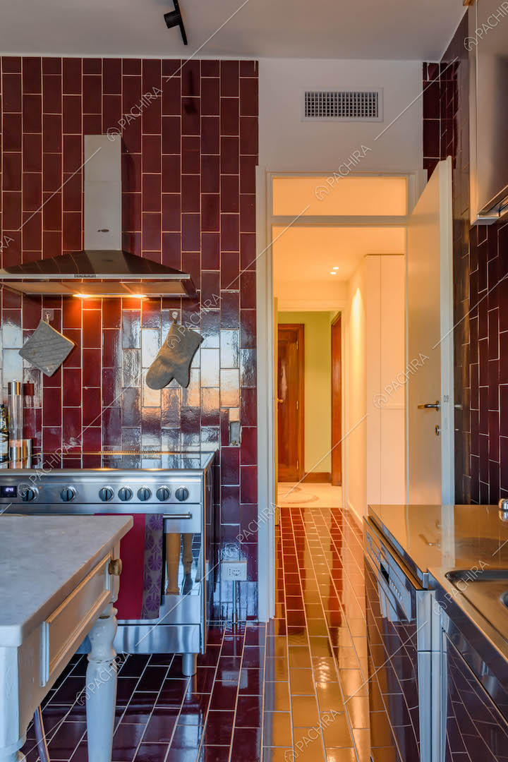 Pavimento e pareti in piastrelle rosse nella cucina a parete con tavolo da pranzo