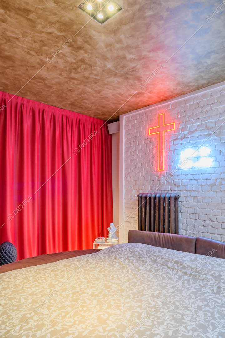 Camera da letto con tenda fucsia, parete bianca in mattoni a vista e letto matrimoniale
