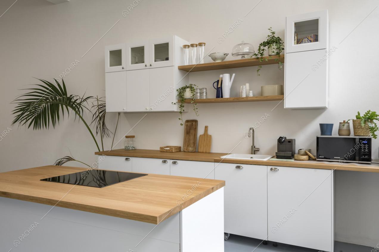 Mobili con cassetti bianchi e piani di lavoro in legno chiaro per la cucina