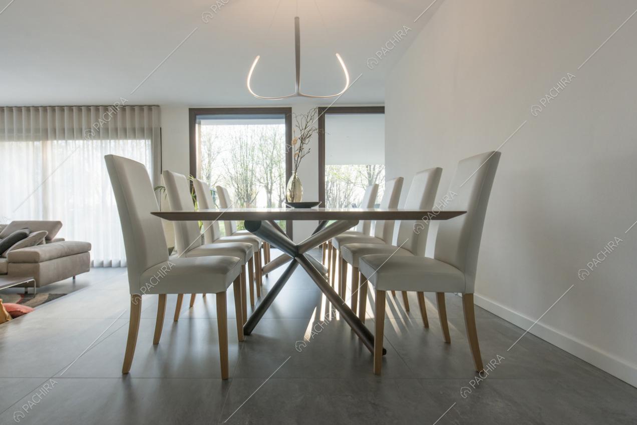 Tavolo da pranzo in luminosa sala con vetrate e pareti e soffitto bianchi