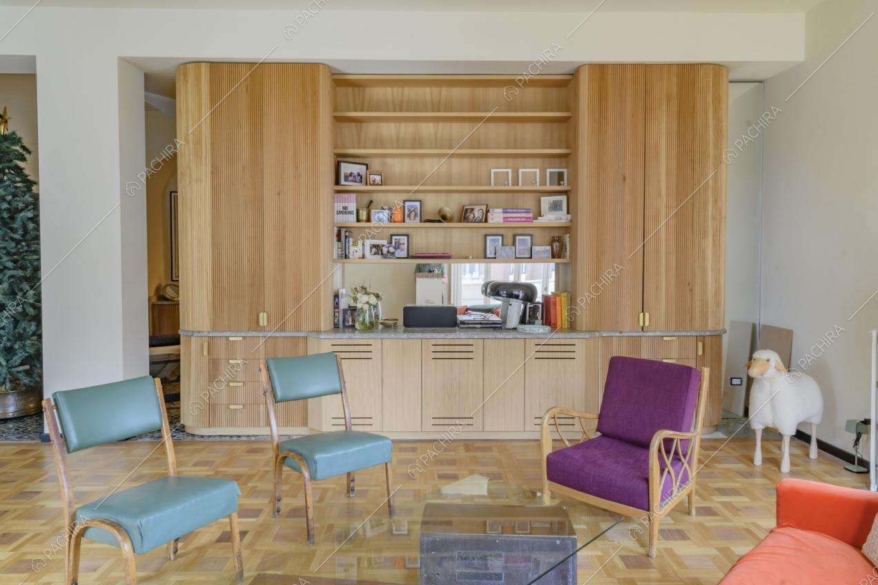 Poltrone colorate nel soggiorno con pavimento in parquet, pareti bianche e libreria a muro