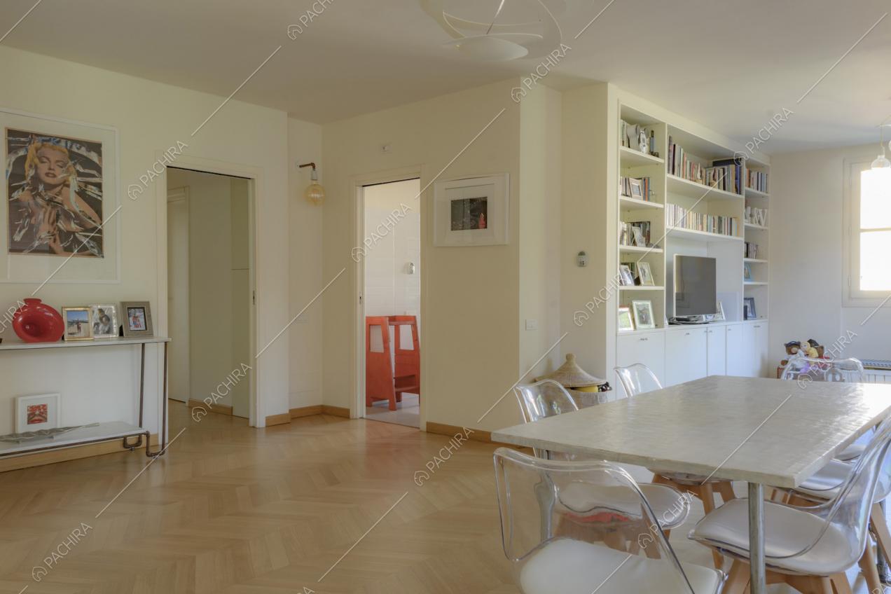 Tavolo da pranzo rettangolare, libreria con televisore e quadro moderno appeso alla parete