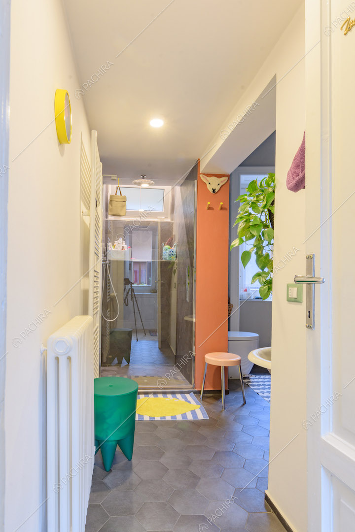 Bagno con pavimento in cementine grigie, box doccia e pareti bianche
