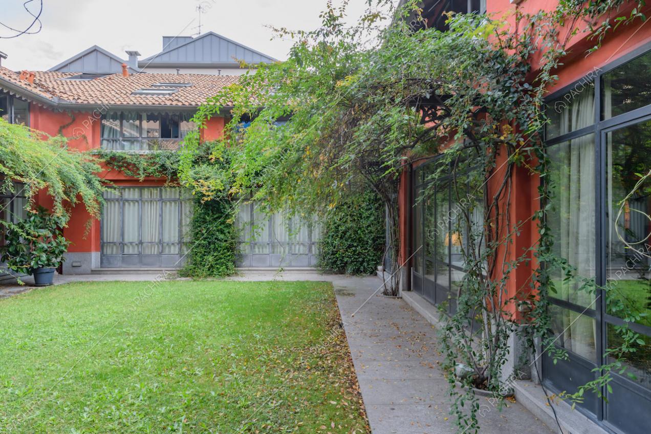 Giardino con rampicanti e vista sugli esterni rossi e sulle vetrate