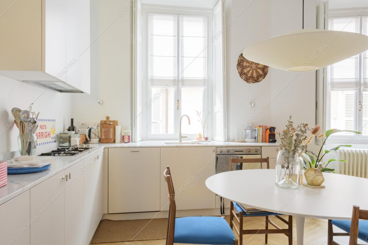 Cucina bianca a muro con fornelli a gas e lampadario di design