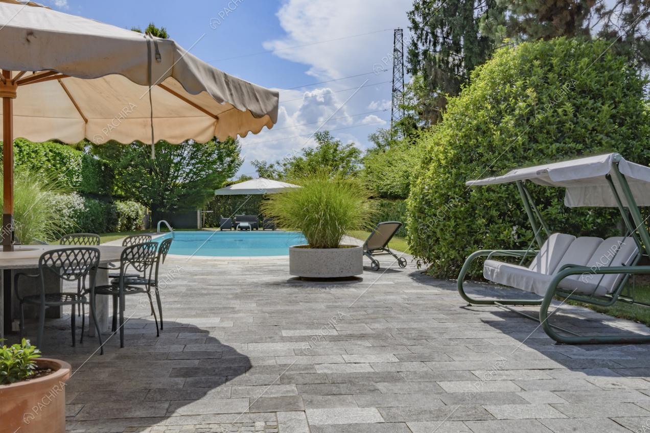 Vista sulla piscina dal giardino con pavimento in pietra