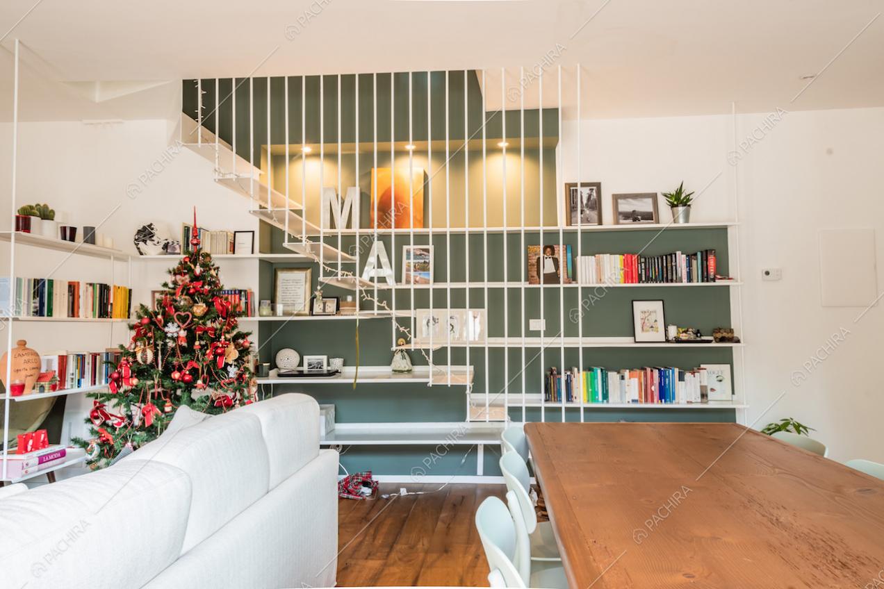 Libreria con mensole bianche su parete colore verde