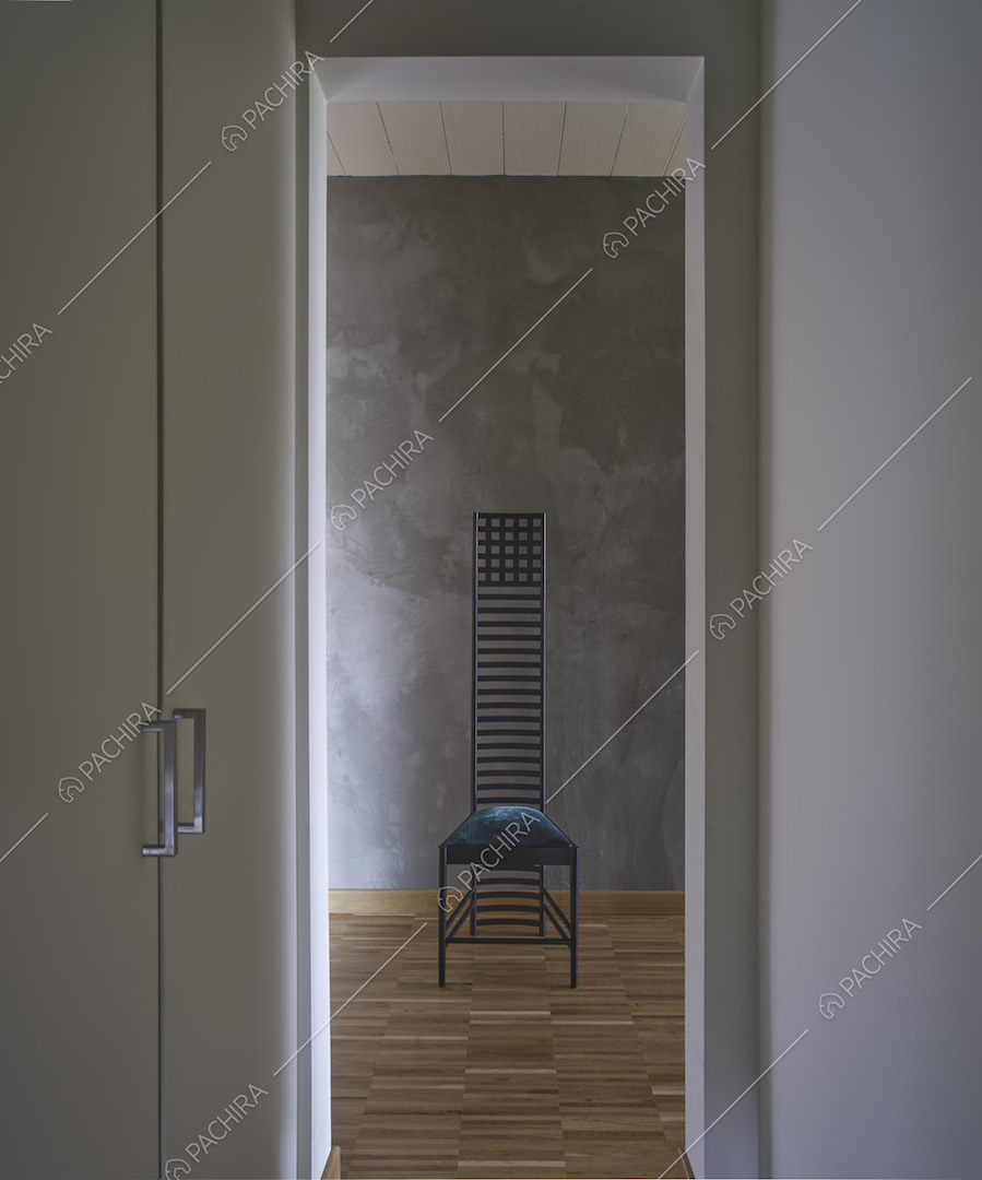Dal corridoio con pavimento in parquet vista su sedia nera di design