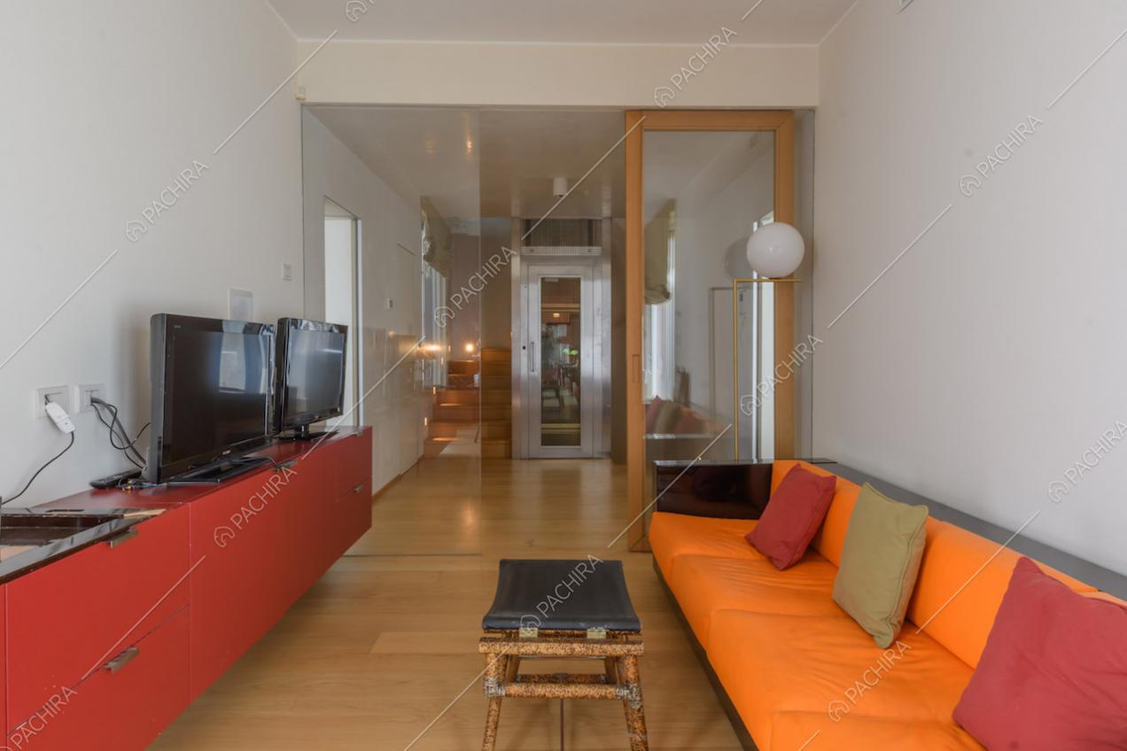 Studio con divano arancione e nero e pavimento in parquet