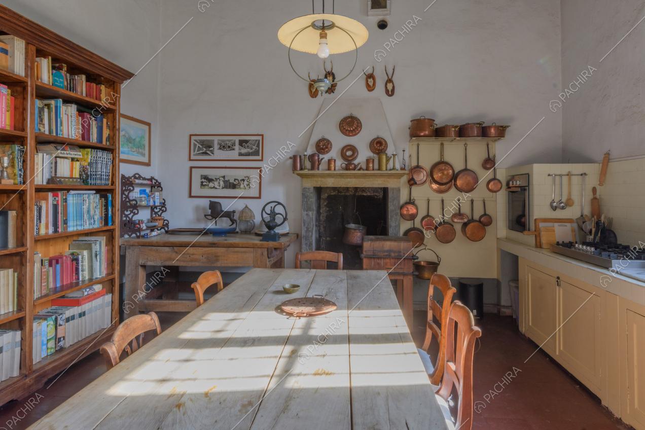 Tavolo da pranzo in legno nella cucina a parete con fornelli a gas e camino
