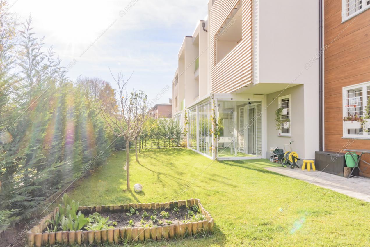 Piccola aiuola nel giardino e scorcio della veranda che funge da palestra
