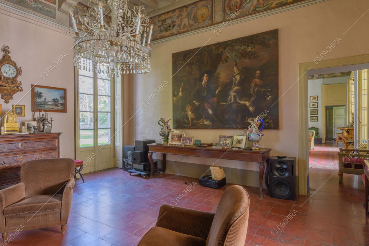 Salotto con pavimento in piastrelle rosse, lampadario in cristallo, dipinto e porta-finestra