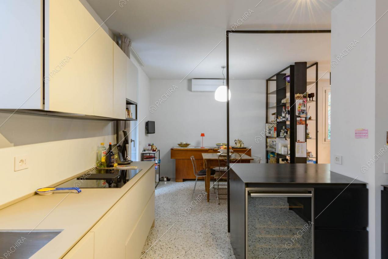 Dalla cucina con fornelli a induzione, pavimento in marmo e pareti bianche vista sul tavolo da pranzo