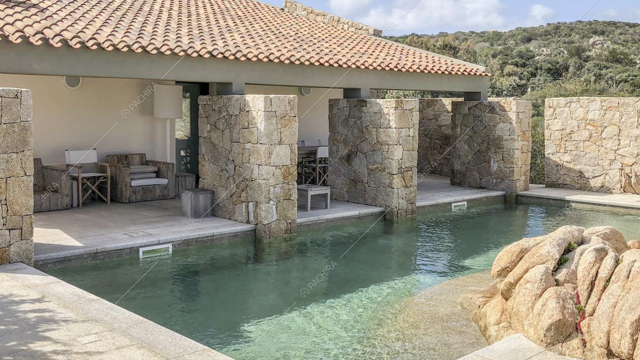 Piscina esterna di fianco al portico circondata da muri in pietra