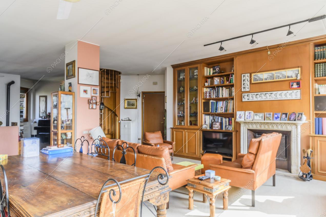 Zona giorno con tavolo da pranzo in legno, divani e poltrone in pelle