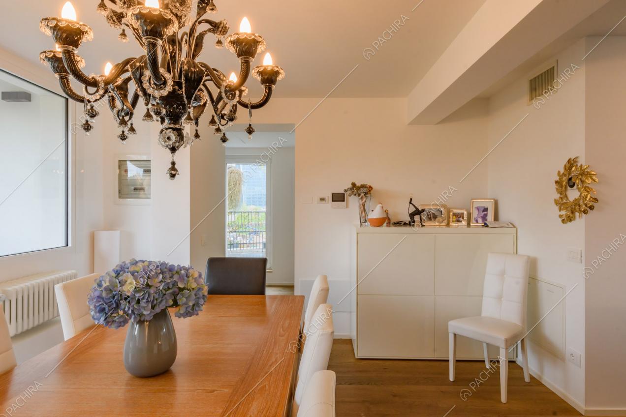 Sedie bianche e tavolo da pranzo in legno nella luminosa zona living con pavimento in parquet