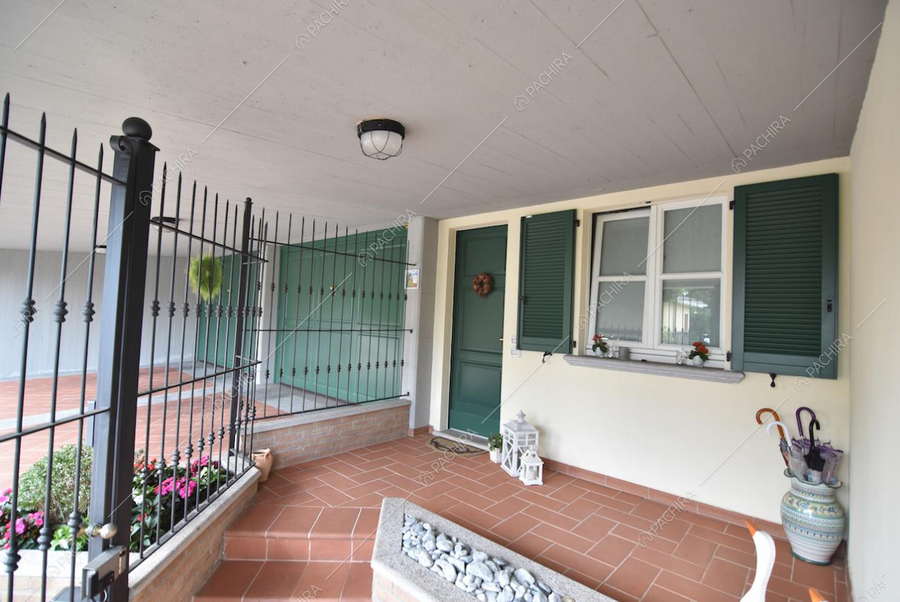 Angolo esterno della villa con ringhiera e finestre con persiane verdi