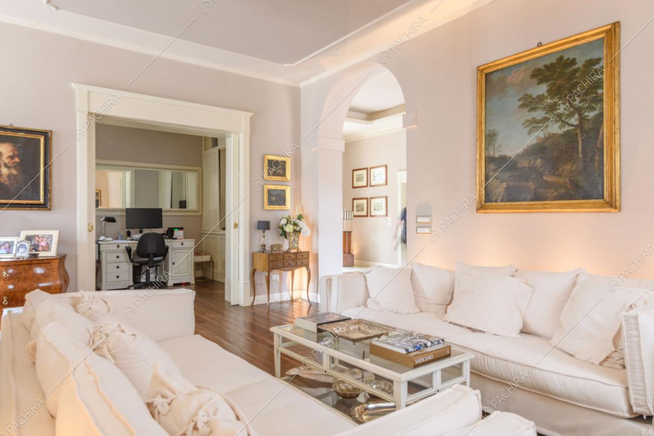 Divani bianchi nella luminosa zona living con pavimento in parquet e vista sullo studio
