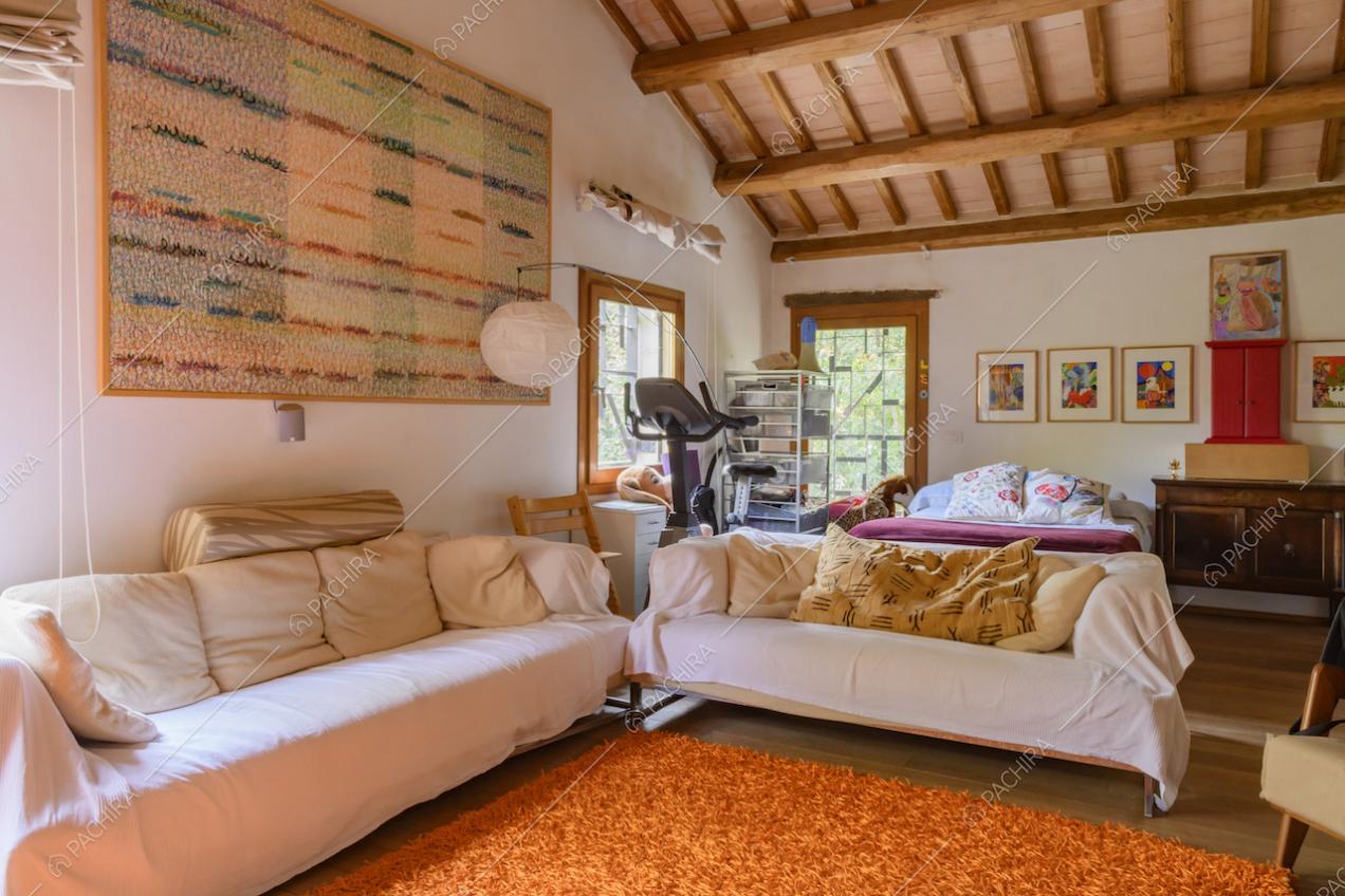 Soffitto con travi a vista, quadro astratto e divani