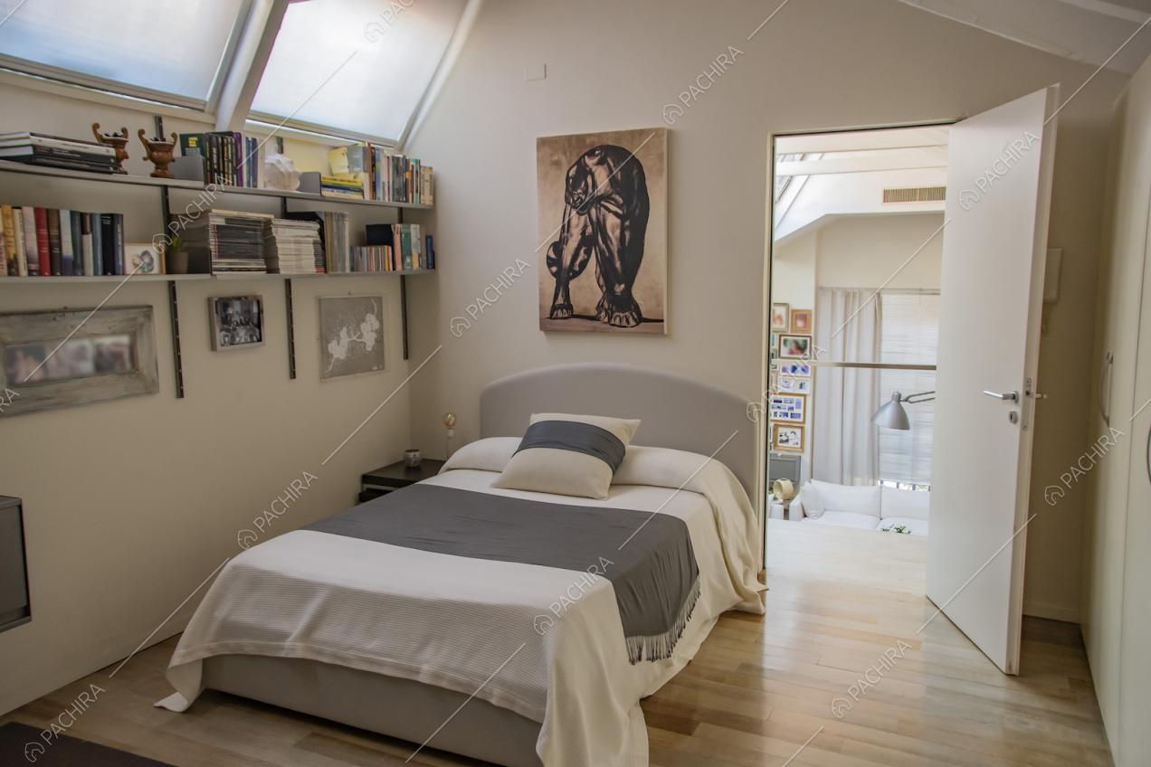 Letto singolo con pareti chiare e quadro appeso sopra alla testata