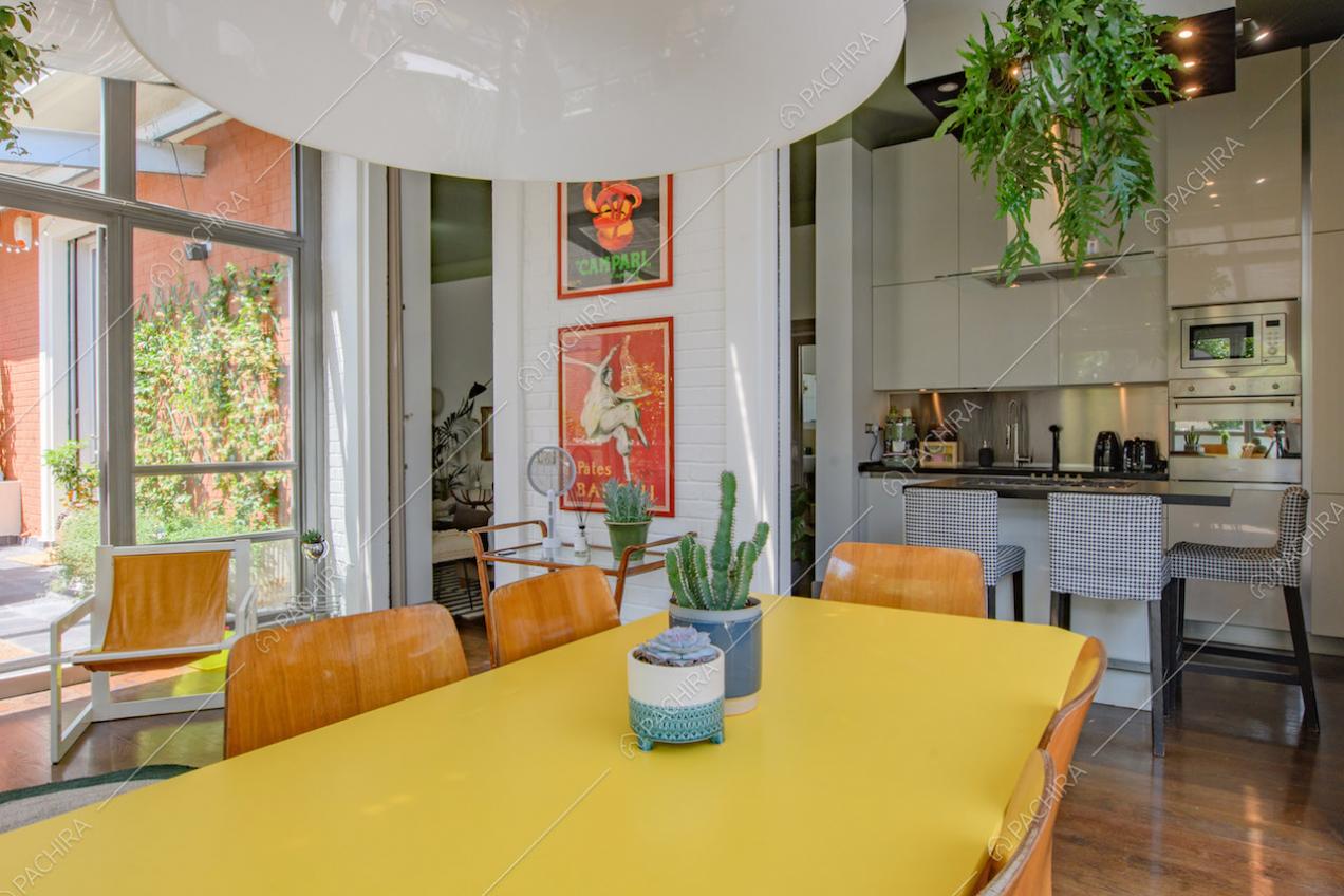 Cucina bianca a vista con isola, pavimento in parquet e tavolo da pranzo giallo